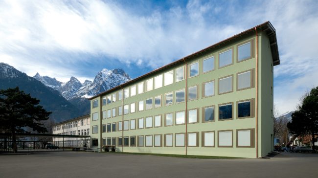 Sanierte Fassade mit Holz-Metall-Fenstern und homogenem grünen Negativabrieb