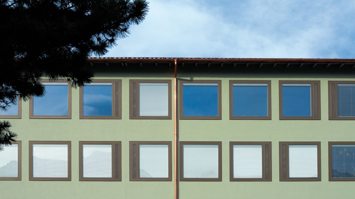 Sanierte Fassade mit Holz-Metall-Fenstern und homogenem grünen Negativabrieb